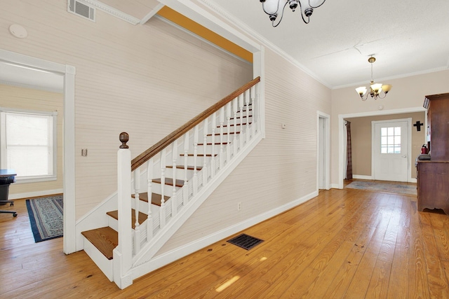 foyer with hardwood / wood-style flooring, ornamental molding, and a notable chandelier