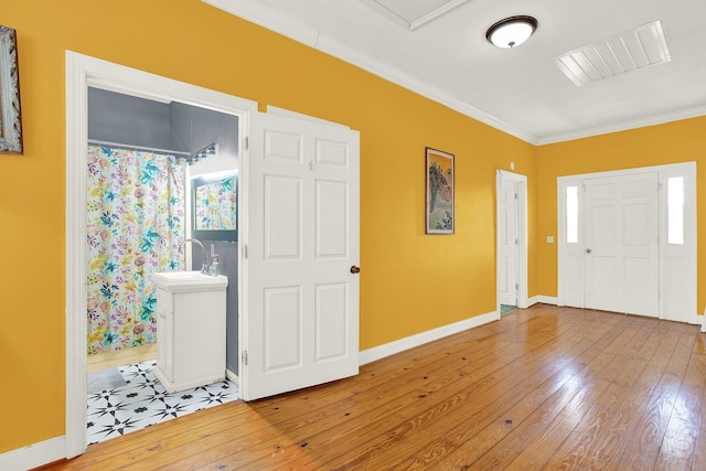 entryway with sink, light hardwood / wood-style flooring, and ornamental molding