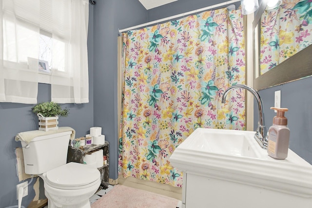 bathroom with toilet, curtained shower, and sink