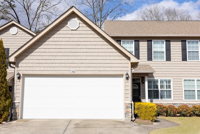 view of front of property with stone siding, roof with shingles, an attached garage, and concrete driveway