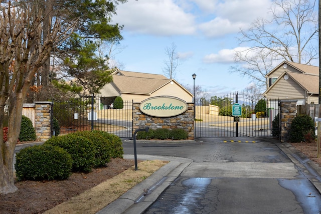 view of road with a gate, a gated entry, street lights, and curbs