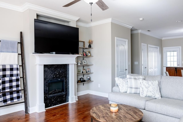 living room with a tile fireplace, wood finished floors, a ceiling fan, baseboards, and crown molding