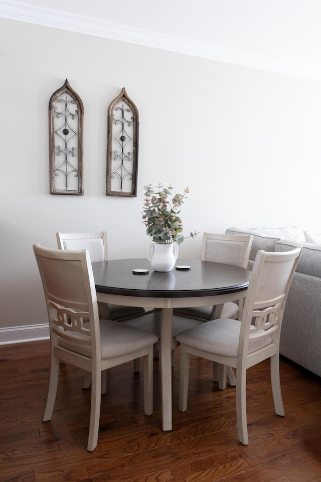 dining area featuring crown molding, baseboards, and wood finished floors