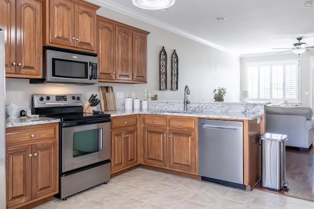 kitchen featuring a peninsula, appliances with stainless steel finishes, brown cabinetry, and crown molding