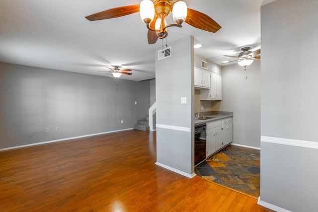 kitchen with dark wood-type flooring, a sink, visible vents, white cabinets, and black dishwasher