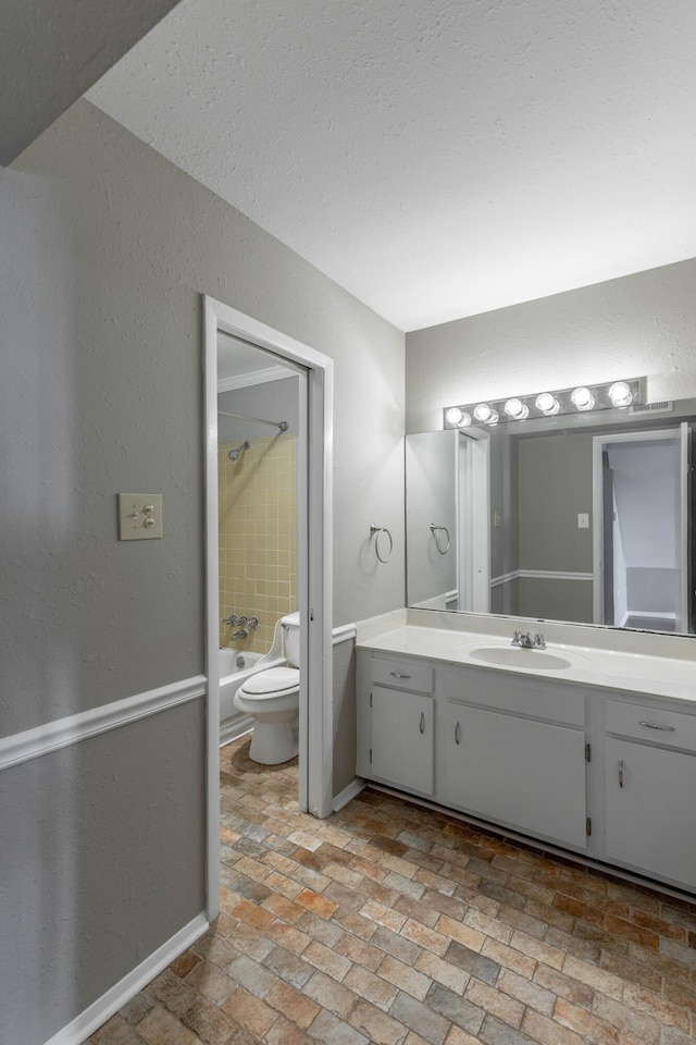 bathroom with toilet, brick floor, shower / tub combination, and vanity