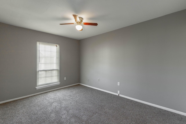 carpeted spare room with a ceiling fan and baseboards