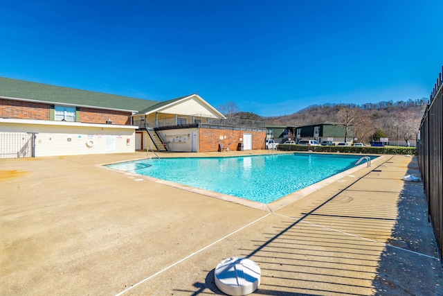 community pool with stairs, a patio, and fence