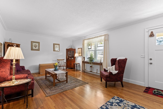 living room with crown molding, a textured ceiling, baseboards, and hardwood / wood-style flooring