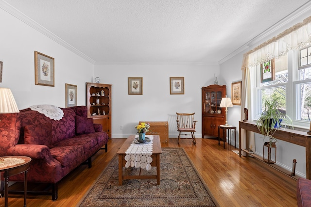 living room featuring ornamental molding, baseboards, a textured ceiling, and hardwood / wood-style floors