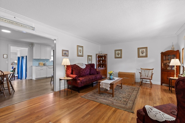 living area with light wood finished floors, a textured ceiling, baseboards, and crown molding