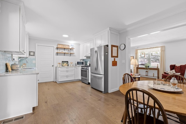 kitchen featuring stainless steel appliances, a sink, visible vents, white cabinetry, and light wood finished floors