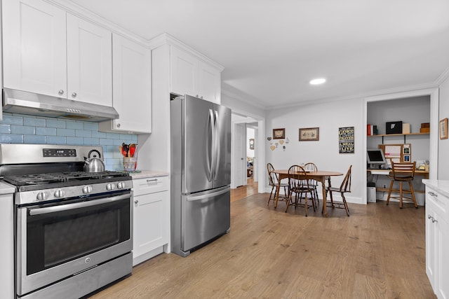 kitchen with light wood-style flooring, decorative backsplash, appliances with stainless steel finishes, white cabinets, and under cabinet range hood