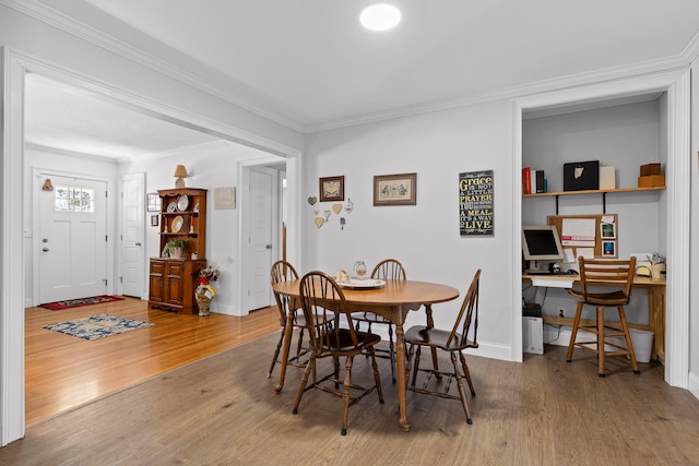 dining area with ornamental molding, wood finished floors, built in desk, and baseboards