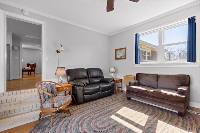 living area featuring ceiling fan, ornamental molding, wood finished floors, and baseboards