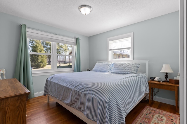 bedroom with multiple windows, baseboards, and wood finished floors