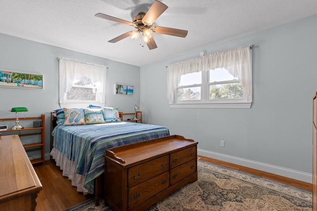 bedroom featuring ceiling fan, a textured ceiling, baseboards, and wood finished floors