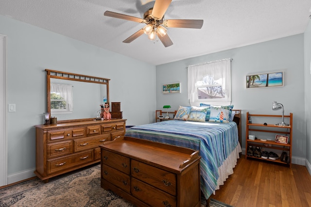 bedroom with dark wood-style floors, a ceiling fan, baseboards, and a textured ceiling