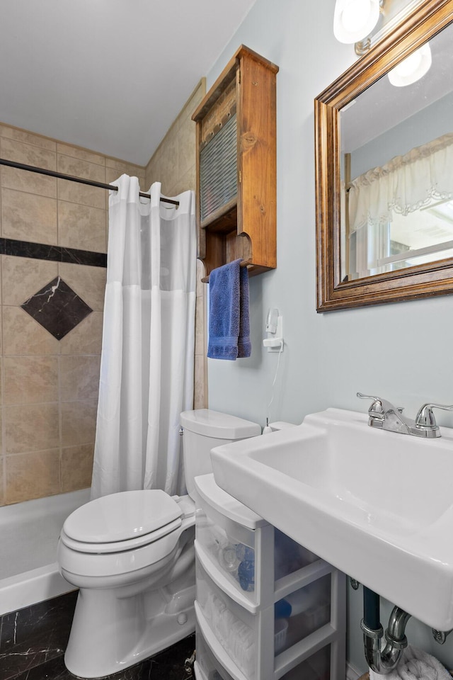 bathroom with a tile shower and toilet