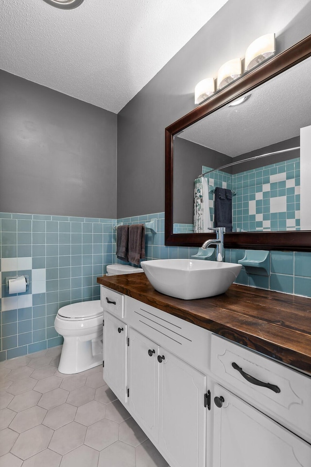 bathroom featuring tile walls, tile patterned flooring, a textured ceiling, and toilet