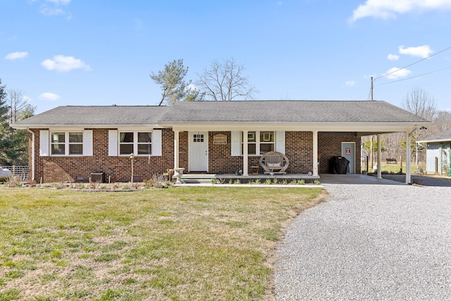 single story home featuring a shingled roof, gravel driveway, a front lawn, a carport, and brick siding