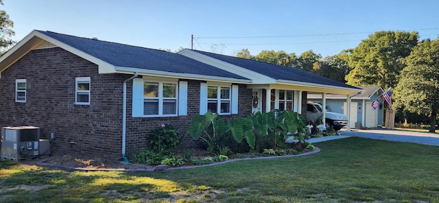 view of front of house with central air condition unit, brick siding, gravel driveway, and a front yard