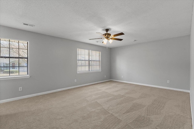 carpeted empty room with plenty of natural light, a textured ceiling, and ceiling fan