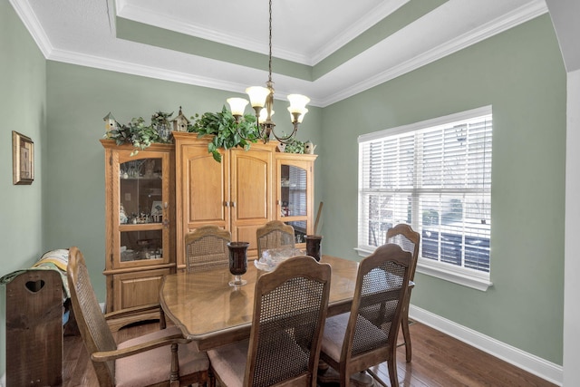 dining area featuring baseboards, a raised ceiling, dark wood finished floors, an inviting chandelier, and crown molding