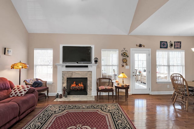 living room with vaulted ceiling, wood finished floors, a high end fireplace, and a wealth of natural light