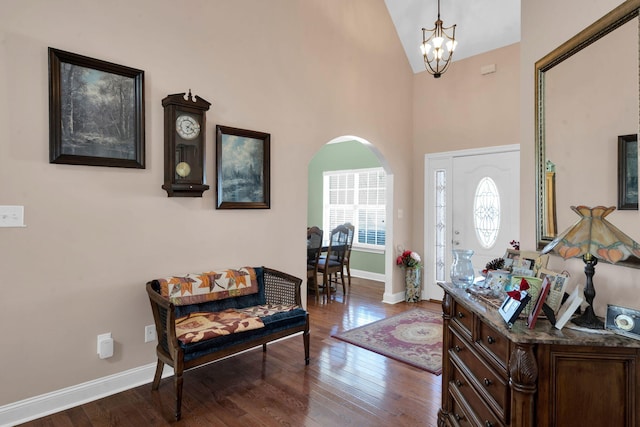 foyer with a chandelier, arched walkways, dark wood-style flooring, and baseboards