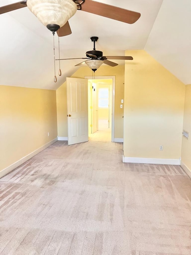 additional living space with vaulted ceiling, light carpet, and baseboards