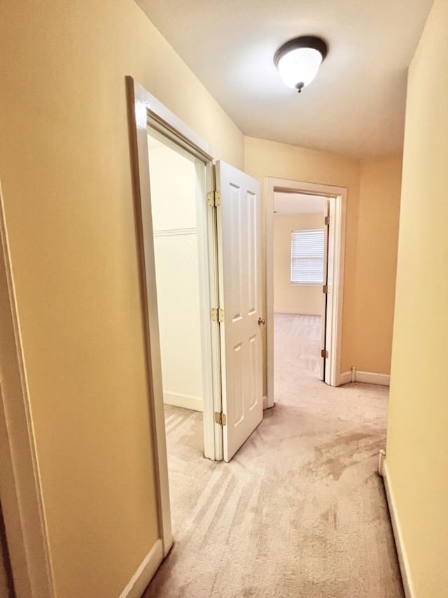 hall featuring light carpet and baseboards