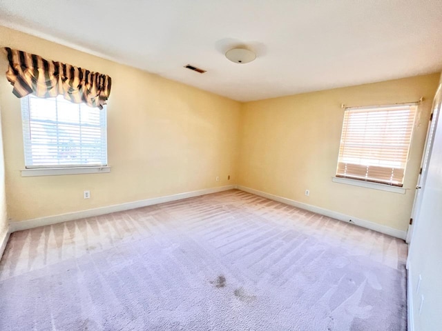 carpeted empty room featuring visible vents and baseboards