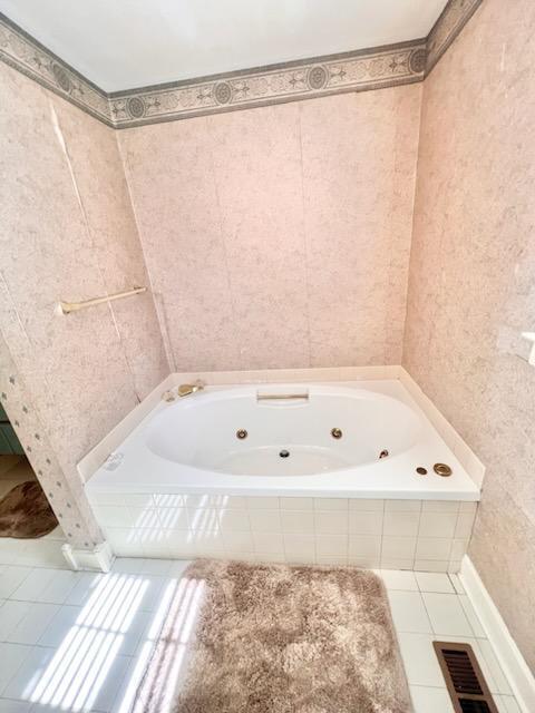 bathroom featuring tile patterned flooring, visible vents, and a jetted tub