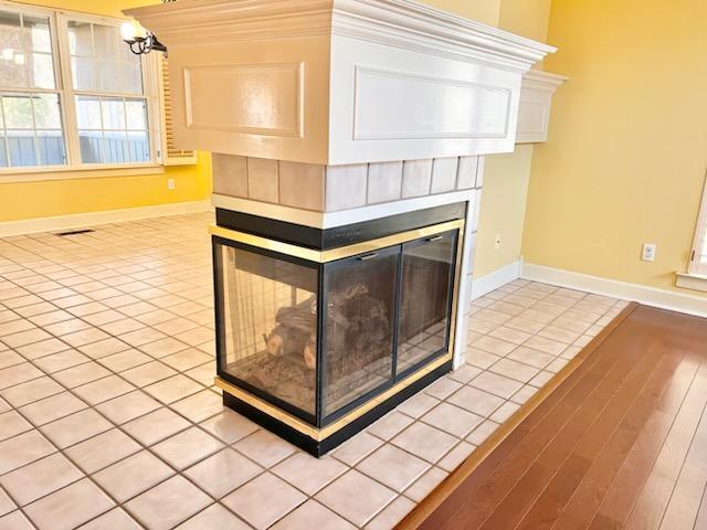 room details featuring visible vents, baseboards, wood finished floors, and a multi sided fireplace