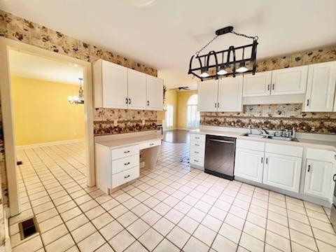 kitchen with dishwashing machine, light countertops, white cabinetry, and decorative light fixtures