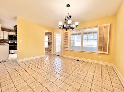 interior space with a chandelier, light tile patterned flooring, visible vents, and baseboards