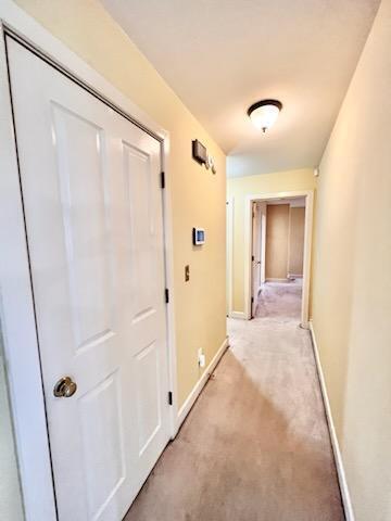 corridor featuring light carpet and baseboards