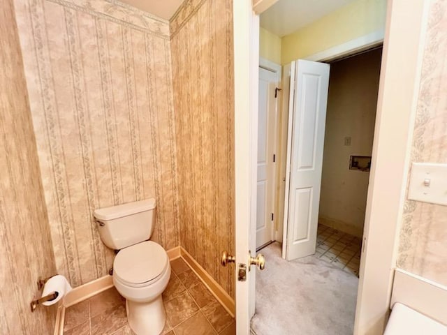bathroom featuring tile patterned flooring, toilet, and baseboards