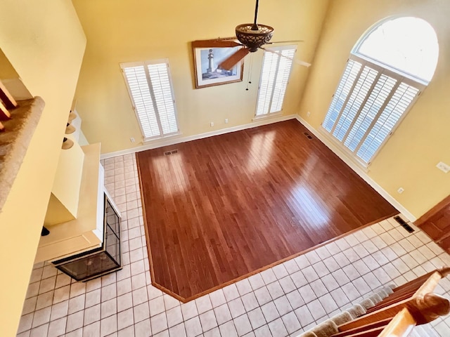 unfurnished living room with a ceiling fan, visible vents, light wood-style flooring, and baseboards