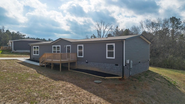 rear view of property with a wooden deck and a lawn