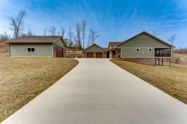 single story home featuring a front yard, a garage, and a sunroom