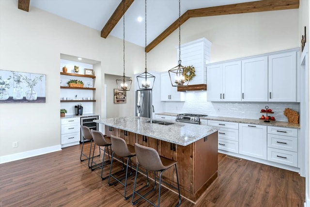 kitchen with a center island with sink, sink, stainless steel appliances, white cabinets, and hanging light fixtures