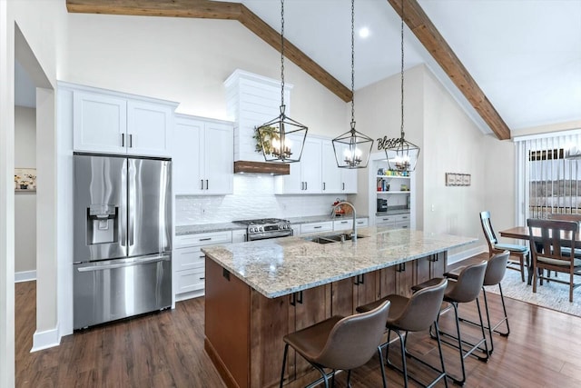 kitchen with an island with sink, white cabinetry, stainless steel appliances, sink, and pendant lighting