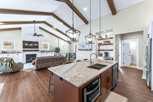 kitchen with appliances with stainless steel finishes, hanging light fixtures, a large fireplace, sink, and a kitchen island with sink