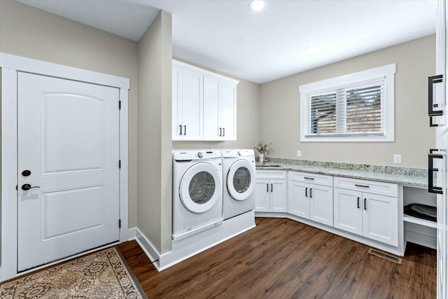 clothes washing area with dark hardwood / wood-style flooring, sink, separate washer and dryer, and cabinets