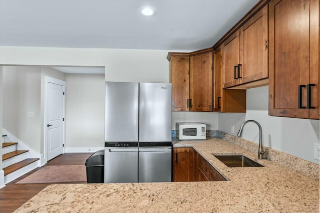 kitchen featuring stainless steel refrigerator, sink, dark wood-type flooring, and light stone countertops