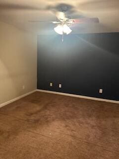 spare room featuring dark carpet and ceiling fan