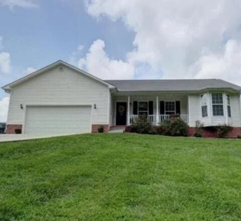 single story home featuring covered porch, a front lawn, and a garage