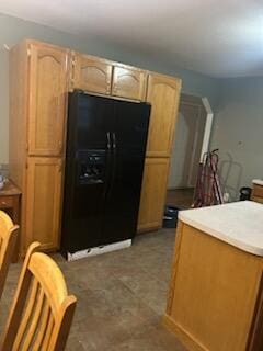 kitchen with black refrigerator with ice dispenser and light brown cabinetry